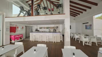 Un moderno vestíbulo de hotel con zona de bar, asientos y equipo de ejercicio.