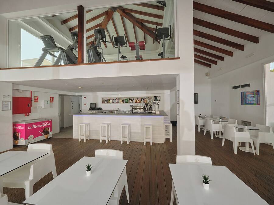 A modern hotel lobby with a bar area, seating, and exercise equipment.