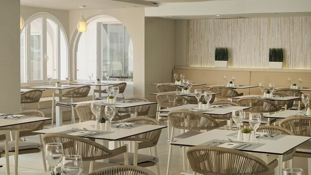 Un restaurante con varias mesas y sillas, amplias ventanas y una decoración interior moderna.