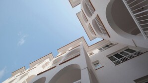 Un edificio de varios pisos con balcones y ventanas, bajo un cielo despejado.