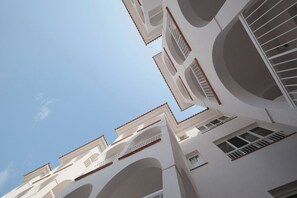 Un edifici de diverses plantes amb balcons i finestres, sota un cel serè.
