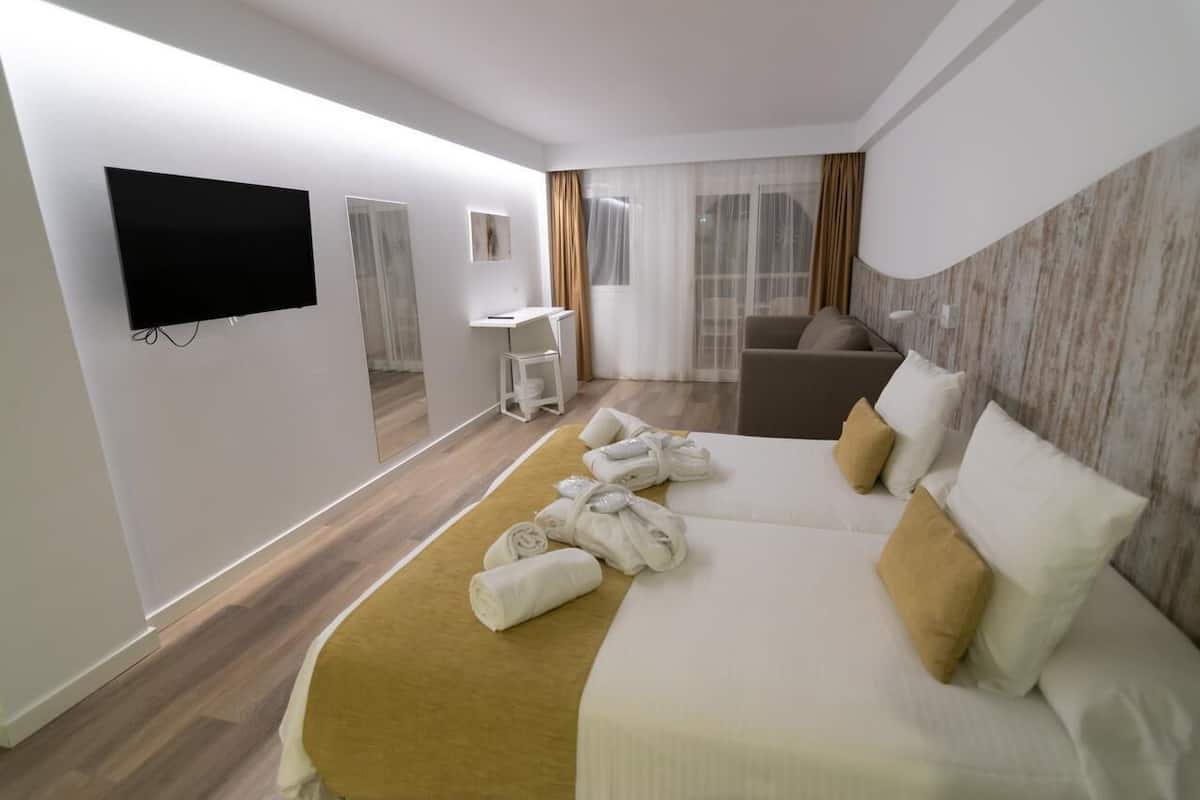 Ein modernes Hotelzimmer mit einem großen Bett, einem Schreibtisch, einer Sitzecke und einem Fernseher.