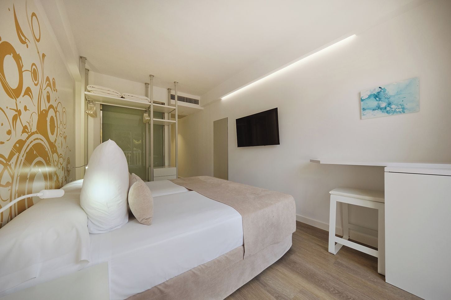 A hotel room with a bed, bedside table, and a television on the wall.