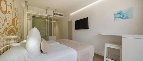 Quarto de hotel com cama, mesa de cabeceira e televisão na parede.