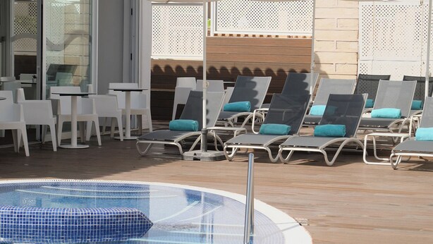 Zona junto a la piscina con sillones de descanso y una piscina.