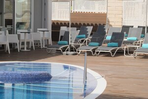 Una piscina al aire libre, sombrillas, sillones reclinables de piscina