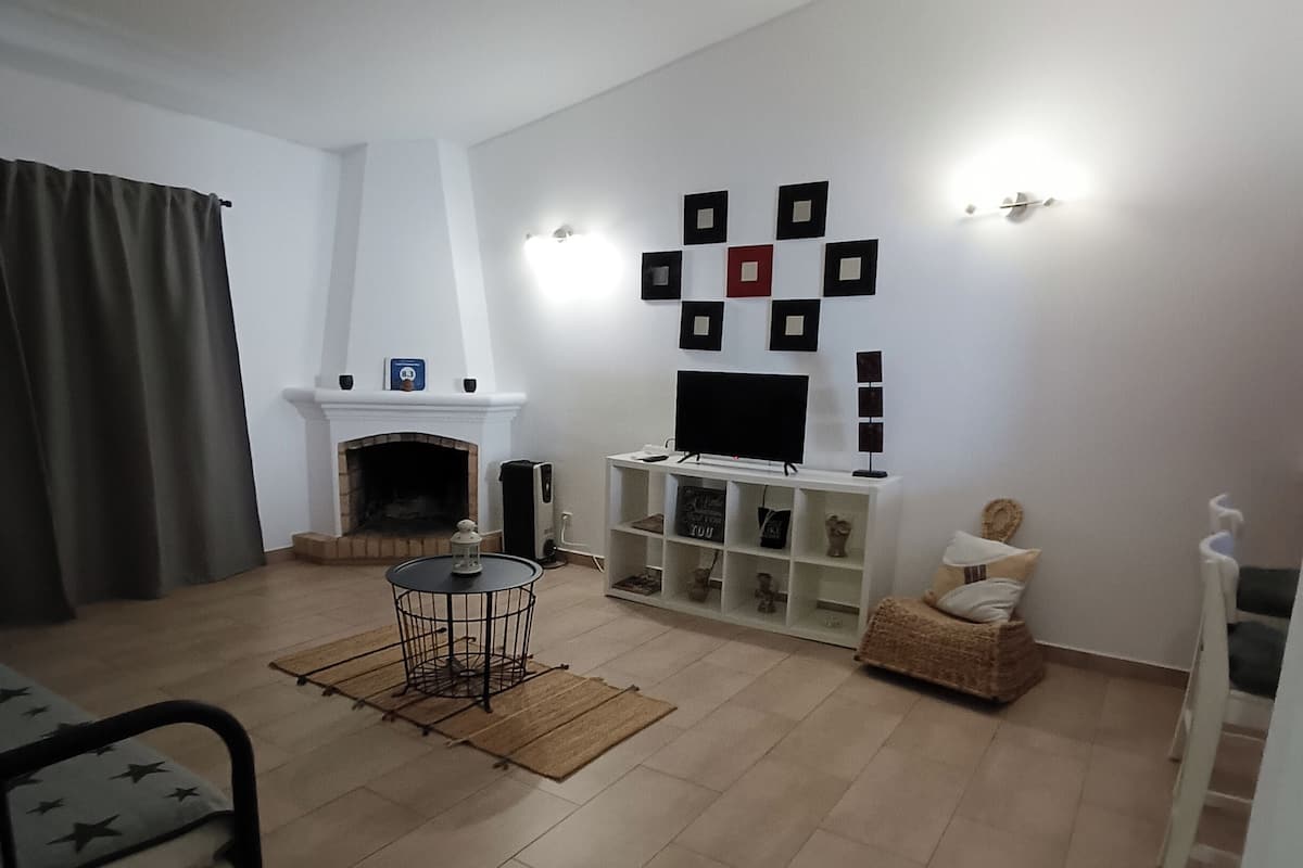 A living room with a fireplace, a TV, and a wall decorated with square frames.