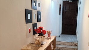 A hallway with a wooden bench, a vase with red flowers, and a glass container with a dessert. - Lagos Charming Villas (Lagos)