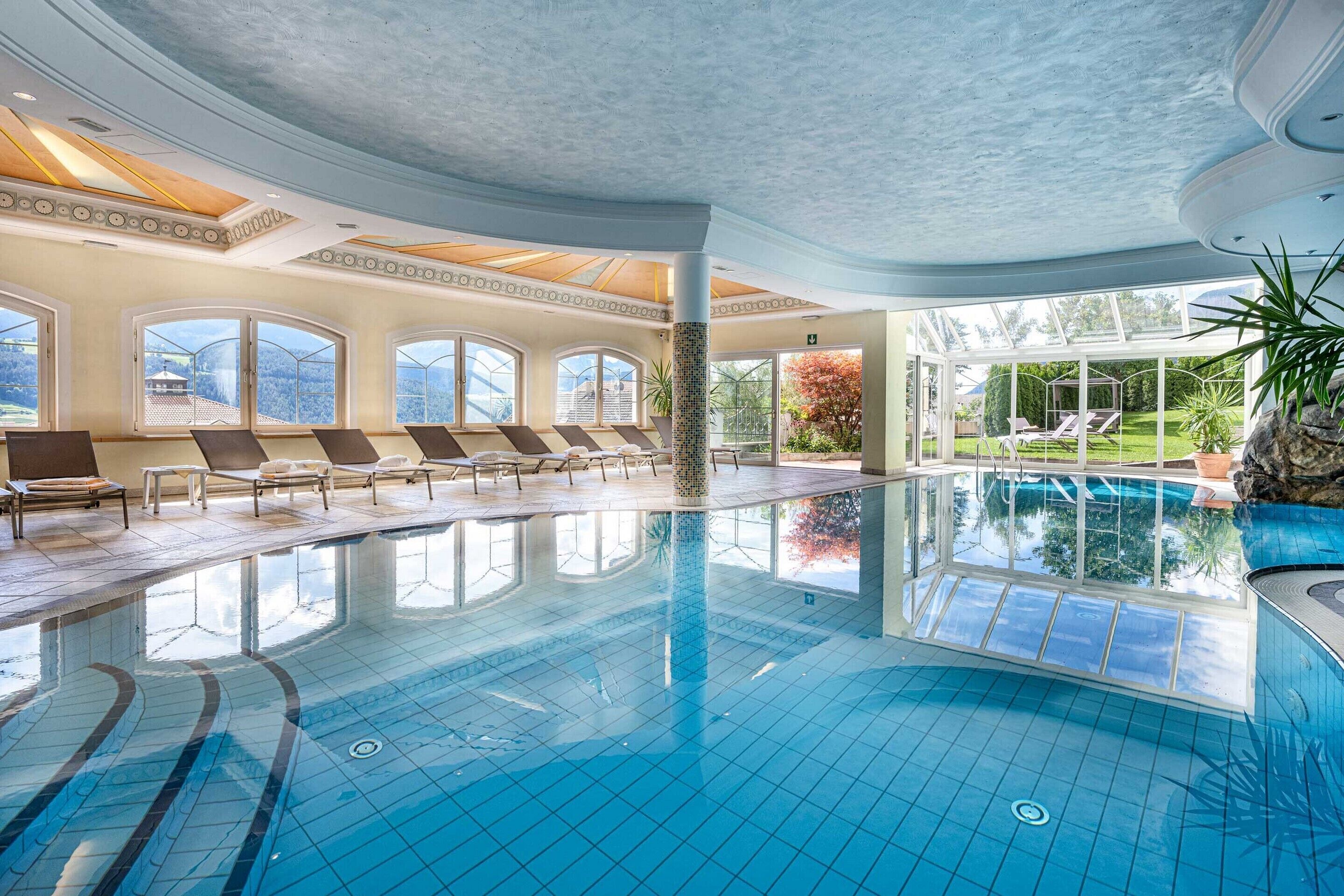Una piscina techada, una piscina al aire libre, sombrillas