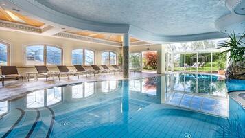 Una piscina techada, una piscina al aire libre, sombrillas