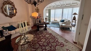 A spacious living room with a large chandelier, a sofa set, a coffee table, and a patterned rug. - Casa Aricò & Shatulle Suites (Taormina)