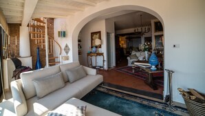 A spacious living room with a high ceiling, a staircase, and an arched doorway leading to another room. - Casa Aricò & Shatulle Suites (Taormina)