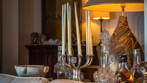 A well-lit room with a sofa, a table with candles, and a decorative lamp. - Casa Aricò & Shatulle Suites (Taormina)