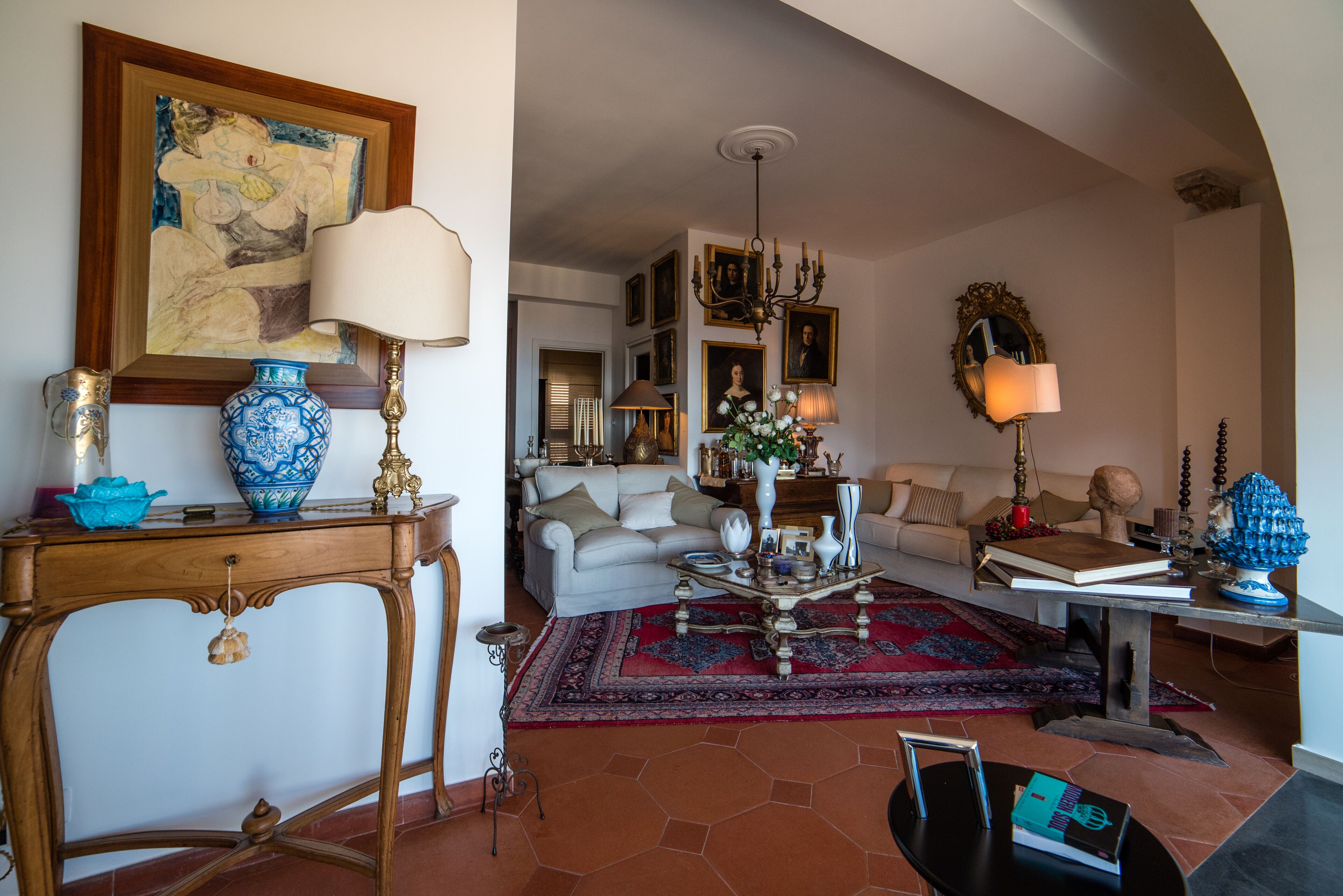 Amplia sala de estar con sofá, mesa de centro y objetos decorativos. Se observa un comedor en el fondo.