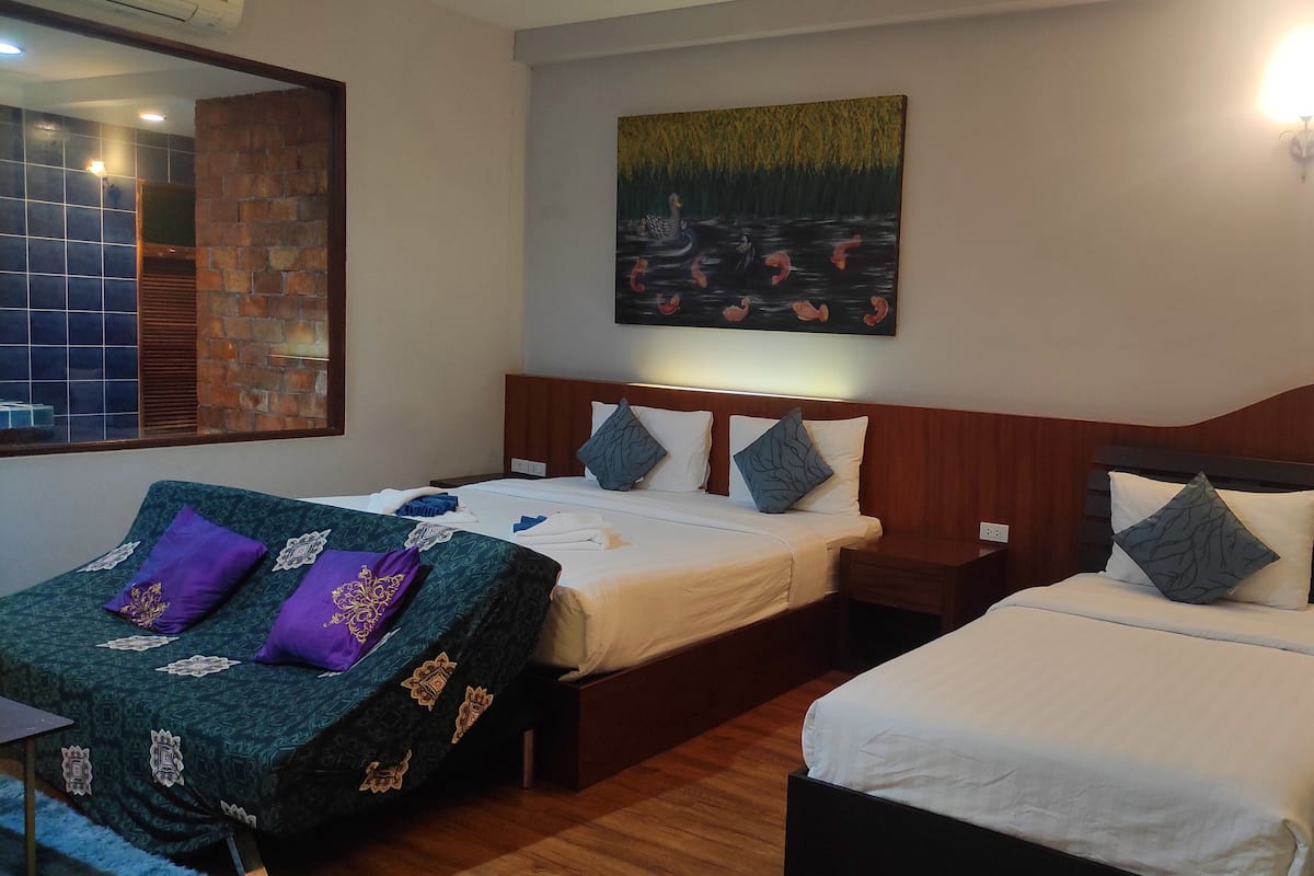 A hotel room with two beds, a large painting, and a view of the outside.