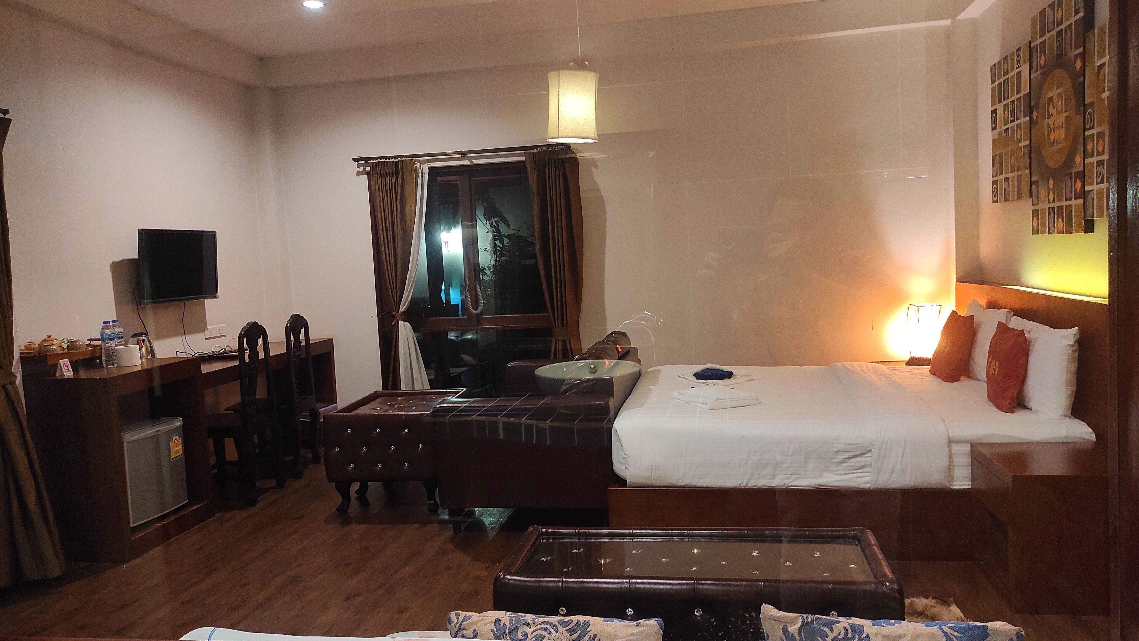 Habitación de hotel con cama, escritorio con televisor, una mesita y una silla.