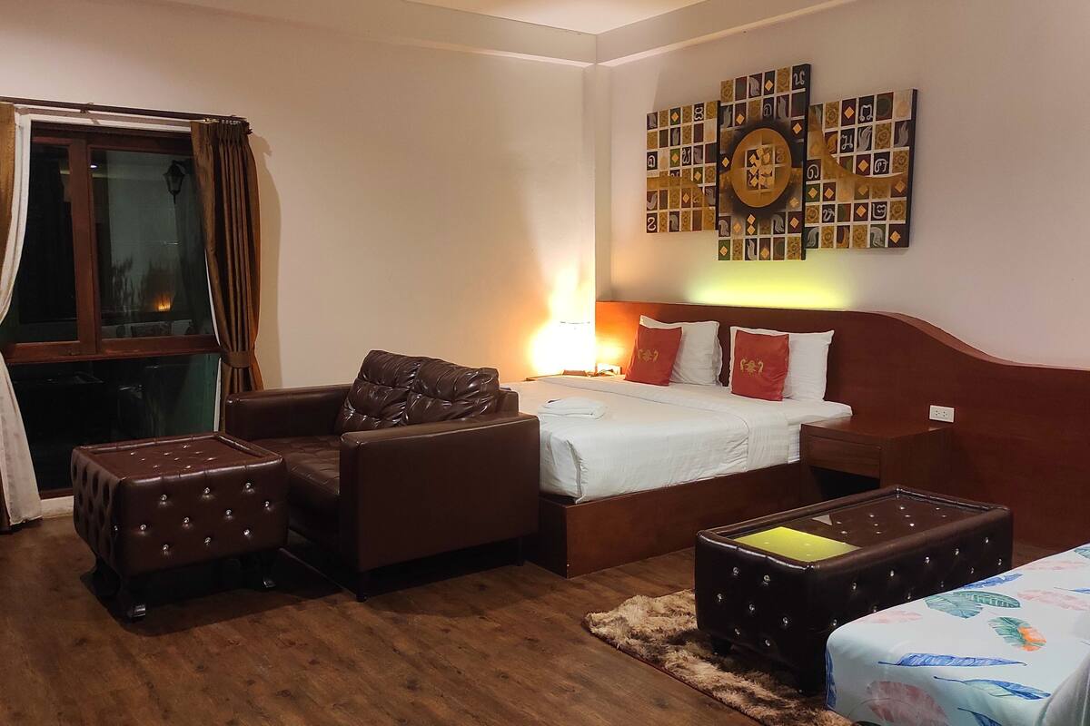 A hotel room with a bed, a sofa, a chair, and a small table.