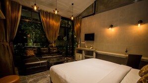 A modern bedroom with a large bed, a sofa, and a desk area.