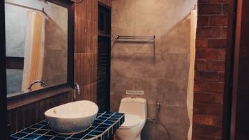 A bathroom with a wooden vanity, a large mirror, a sink, and a shower area.