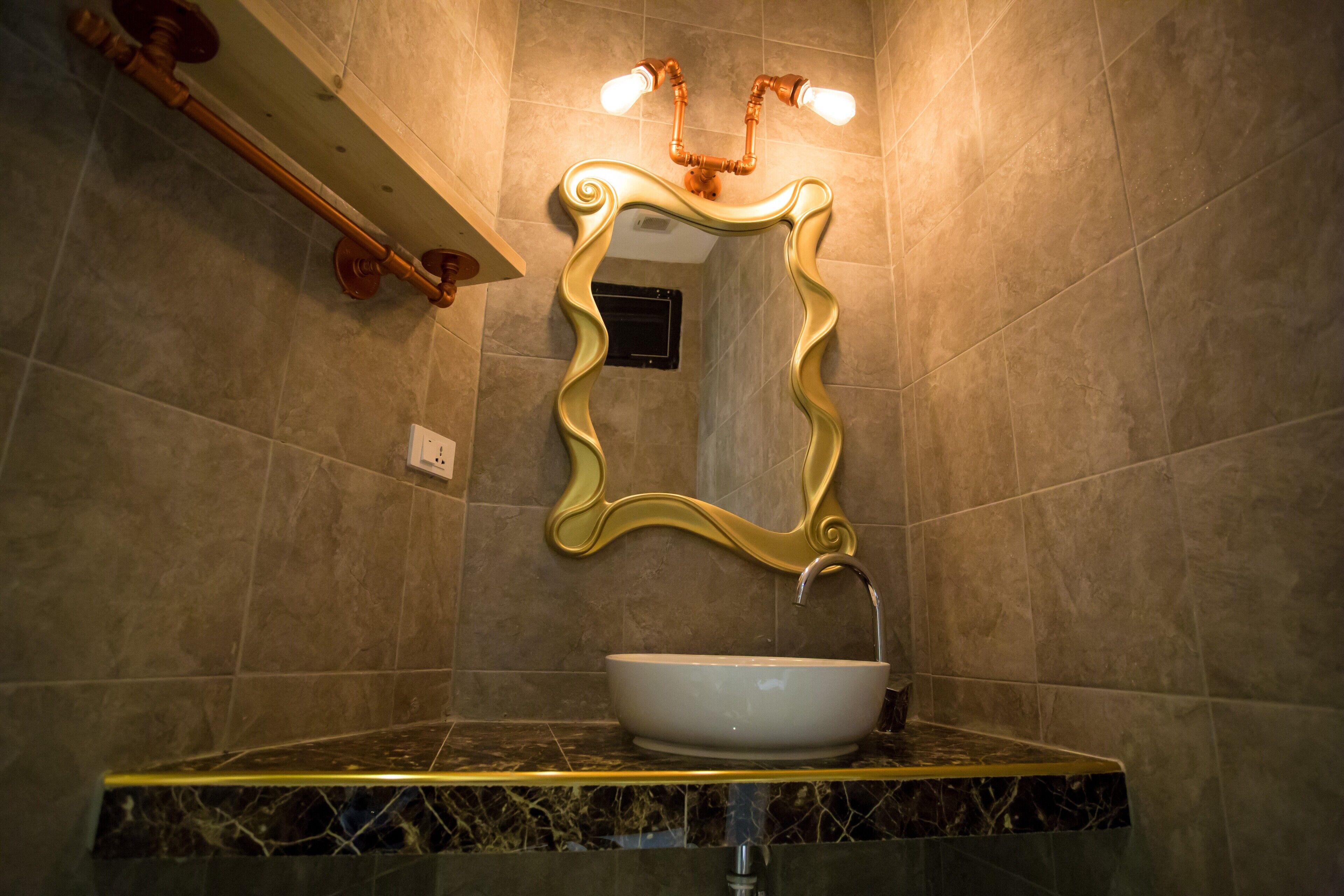 A bathroom with a marble sink, a gold-framed mirror, and a towel rack.