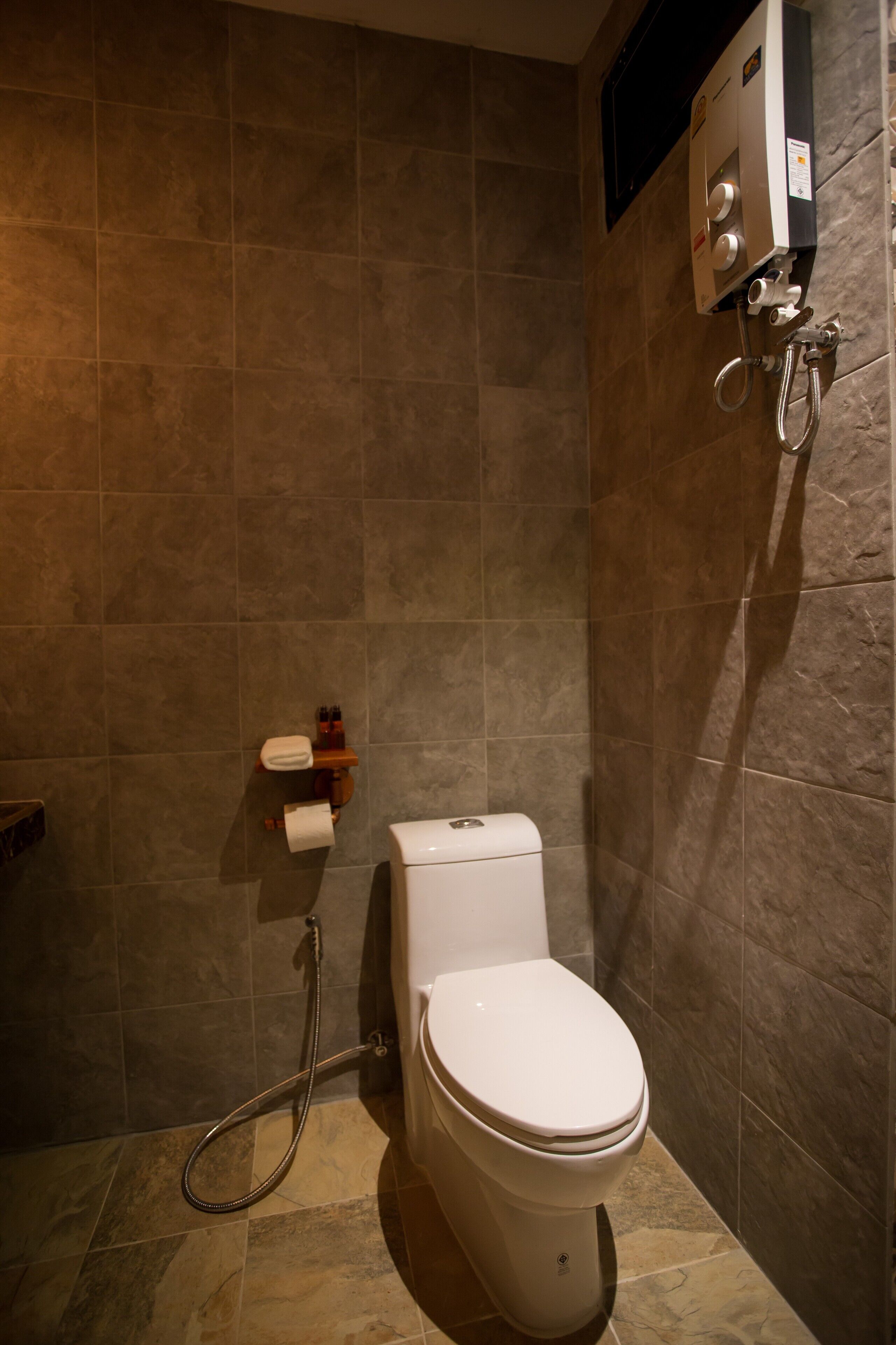 A bathroom with a toilet, a shower unit, and a towel rack.