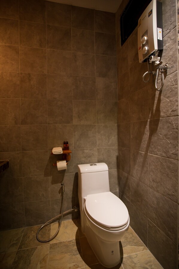 Een badkamer met een toilet, een douche en een handdoekhouder.