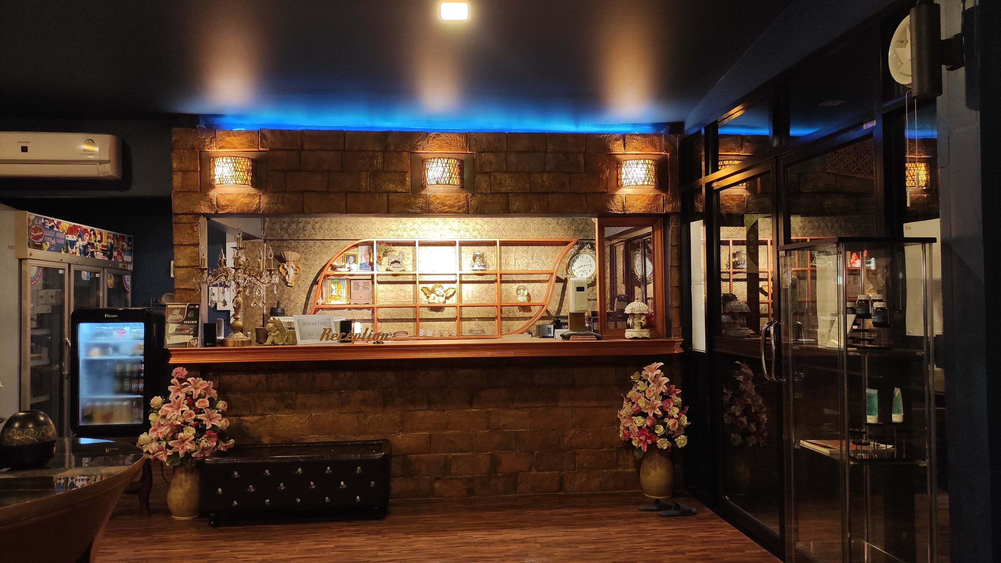 A bar area with a wooden counter, decorative lights, a clock, and a display of various items.