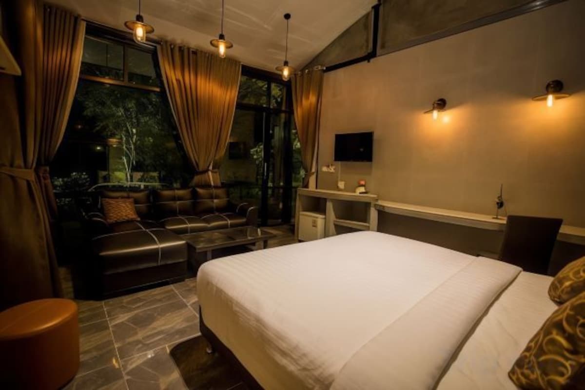 Une chambre d’hôtel moderne, dotée d’un grand lit, d’un canapé, d’un bureau et offrant une vue sur l’extérieur.