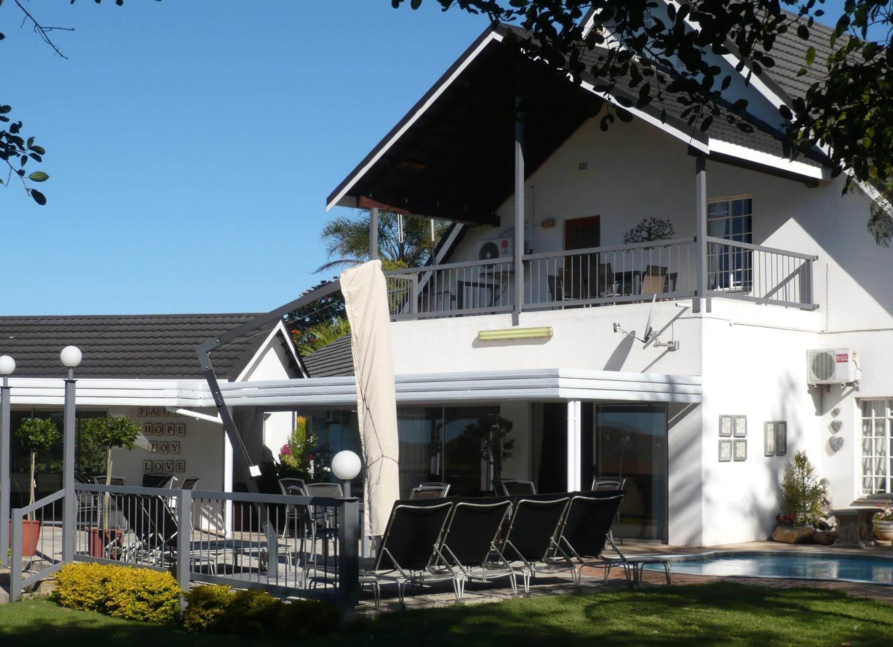 Ein zweistöckiges Gebäude mit Balkon, Außenbereich zum Sitzen und einem Swimmingpool.