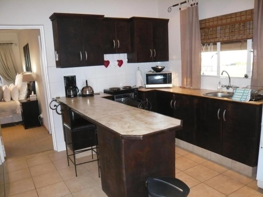 Una cocina con armarios de madera oscura, una isla central con un fregadero, un microondas y un hervidor.