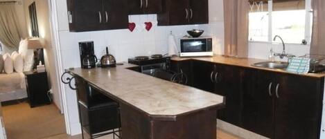 Una cocina con armarios de madera oscura, una isla central con un fregadero, un microondas y un hervidor.