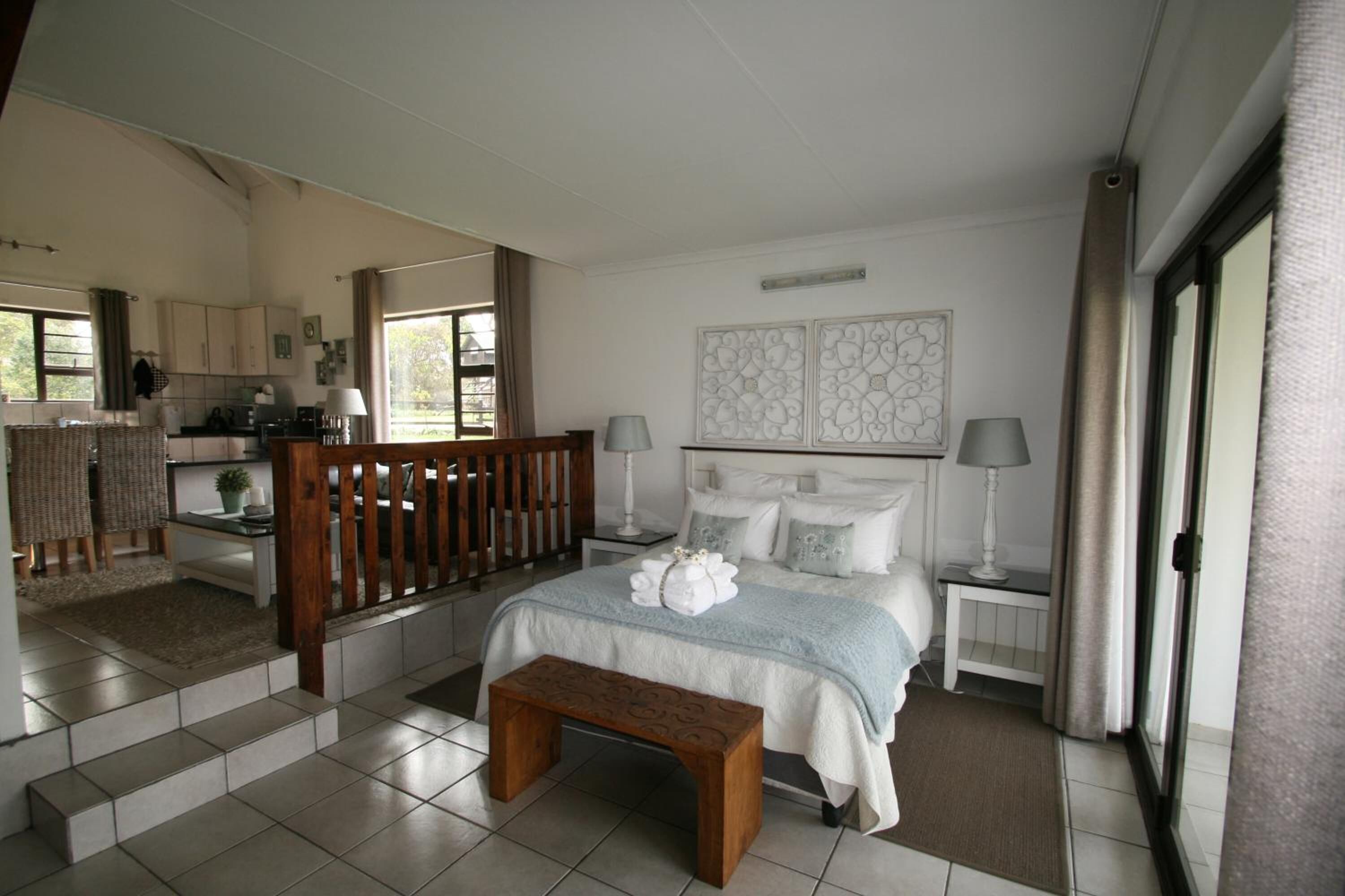 Un dormitorio espacioso con una cama grande, un banco de madera y vistas a la cocina y el comedor.