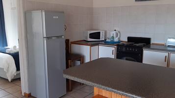 A compact kitchen with a refrigerator, microwave, toaster, and stove.