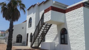 Un edificio con fachada blanca, una escalera y ventanas de arco.