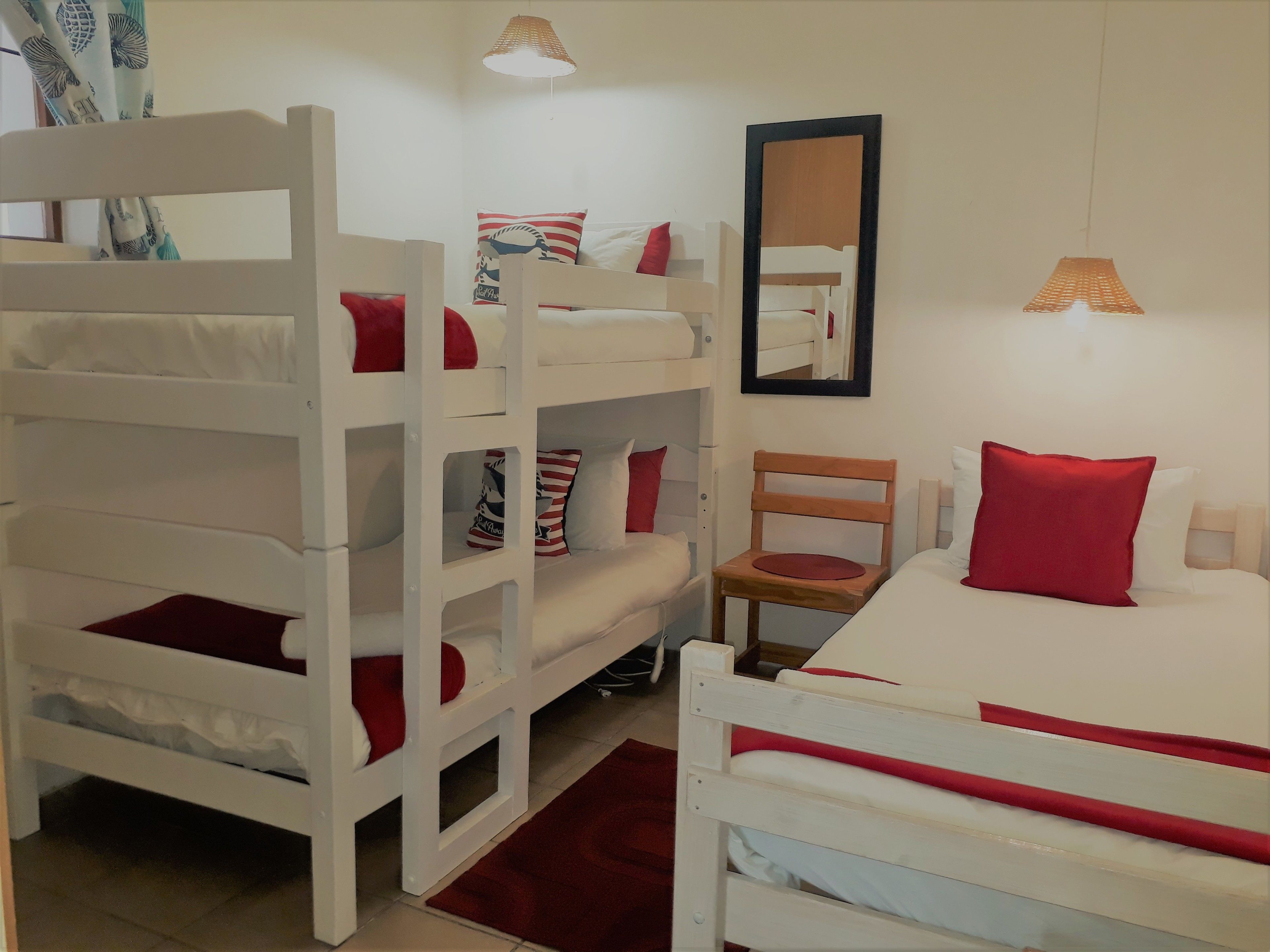 A bunk bed room with a single bed, a chair, and a mirror.