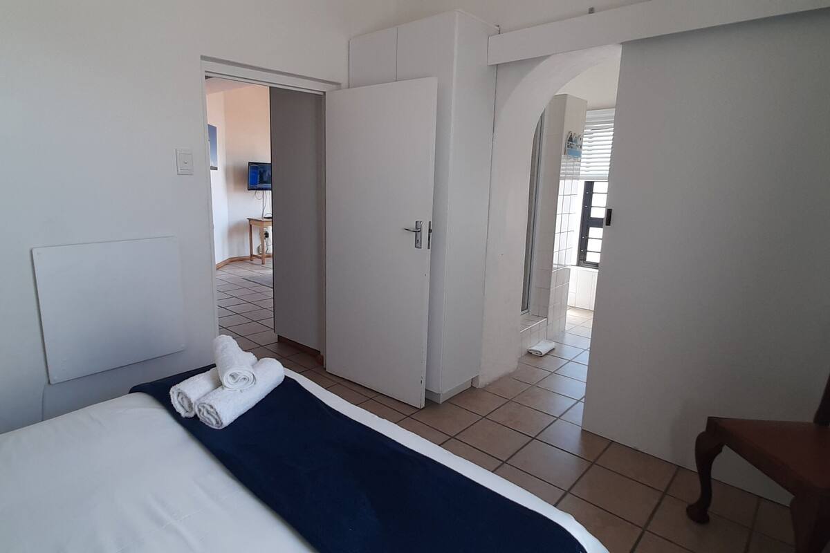 Ein Hotelzimmer mit einem Bett, einem Sessel und einem durchgegangenen Tür erkennbaren Badezimmer.