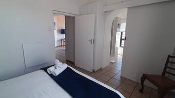 A hotel room with a bed, a chair, and a bathroom visible through an open door.