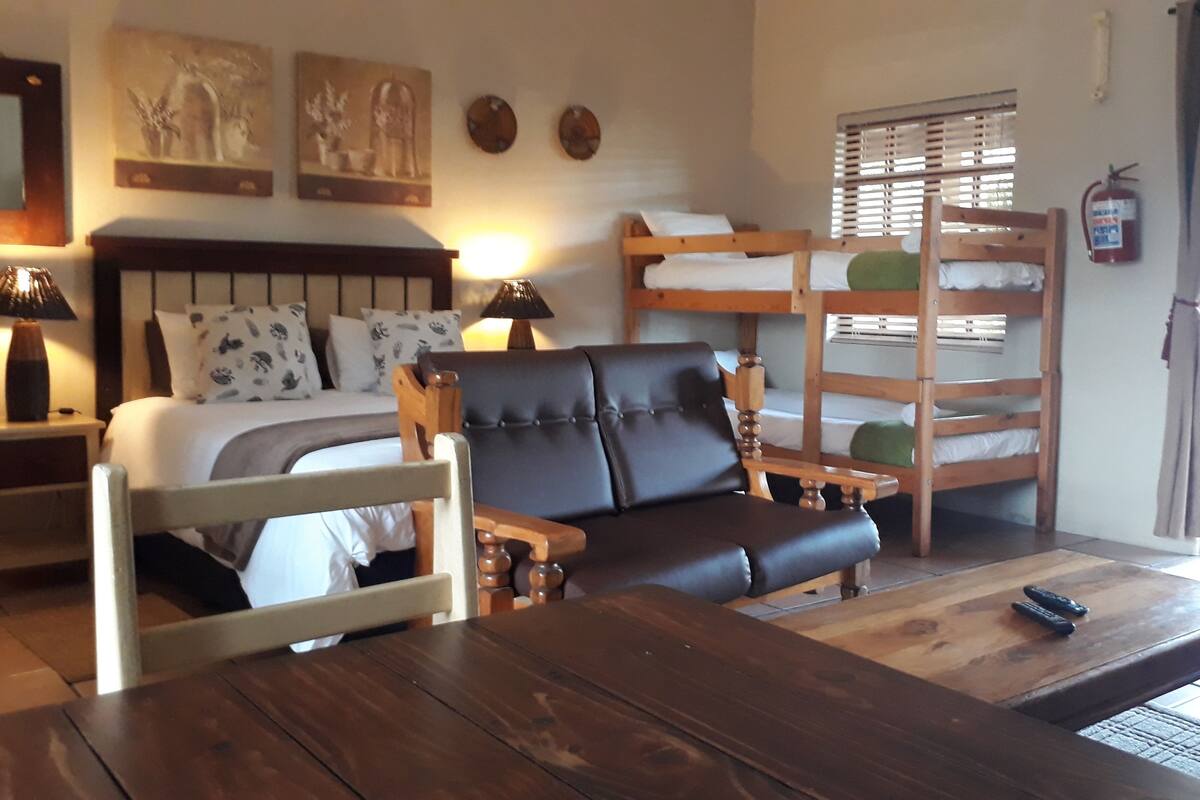 Une pièce confortable avec un lit, un canapé, une table en bois et des lits superposés.