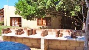 A rustic building with a brick patio and a tree providing shade. - Tourist Lodge Gansbaai (Gansbaai)