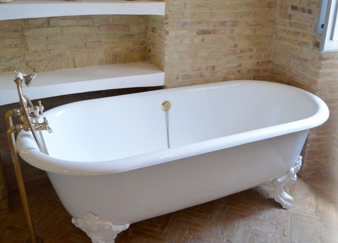 A white freestanding bathtub with claw feet, a gold faucet, and a chain.