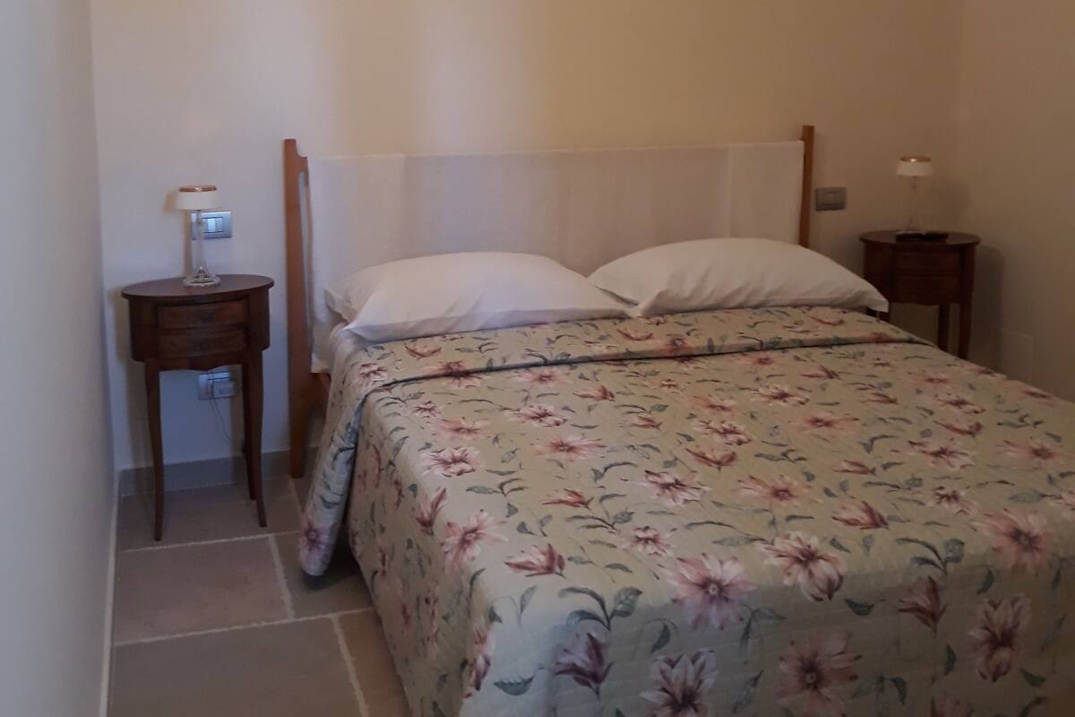 Ein Schlafzimmer mit Bett, Nachttisch und Lampe.