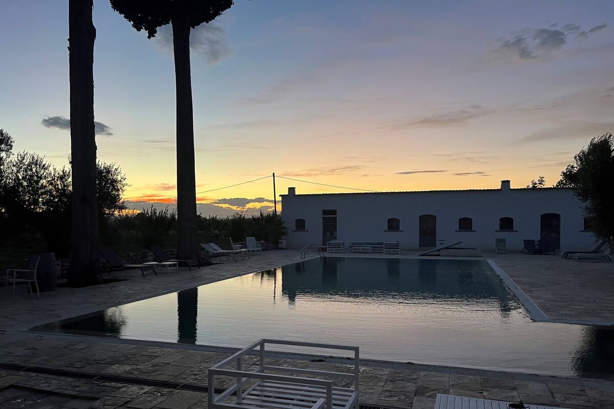 Ein Poolbereich mit Liegestühlen und einem Gebäude im Hintergrund.