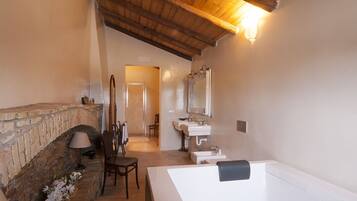 A bathroom with a stone wall, a bathtub, a sink, and a mirror.