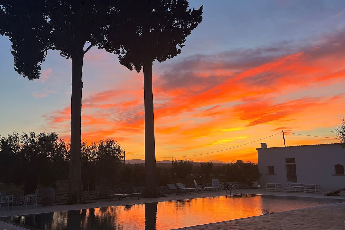 Ein ruhiger Außenbereich mit Pool, Liegestühlen und Blick auf den Sonnenuntergang.