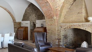 Amplia sala de estar con un alto techo abovedado de ladrillo, sofás de cuero, una mesa de centro de madera y una chimenea.