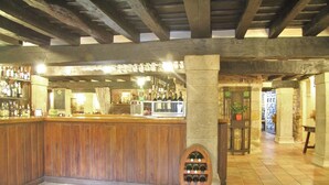 Una zona de bar con mostrador de madera, un botellero y un letrero de restaurante.