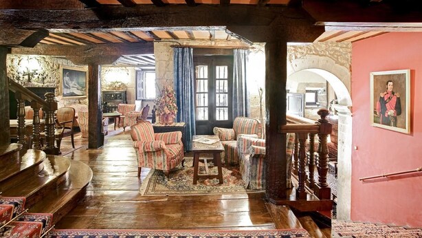 Amplia sala de estar con escalera de madera, chimenea y vista a la cocina.