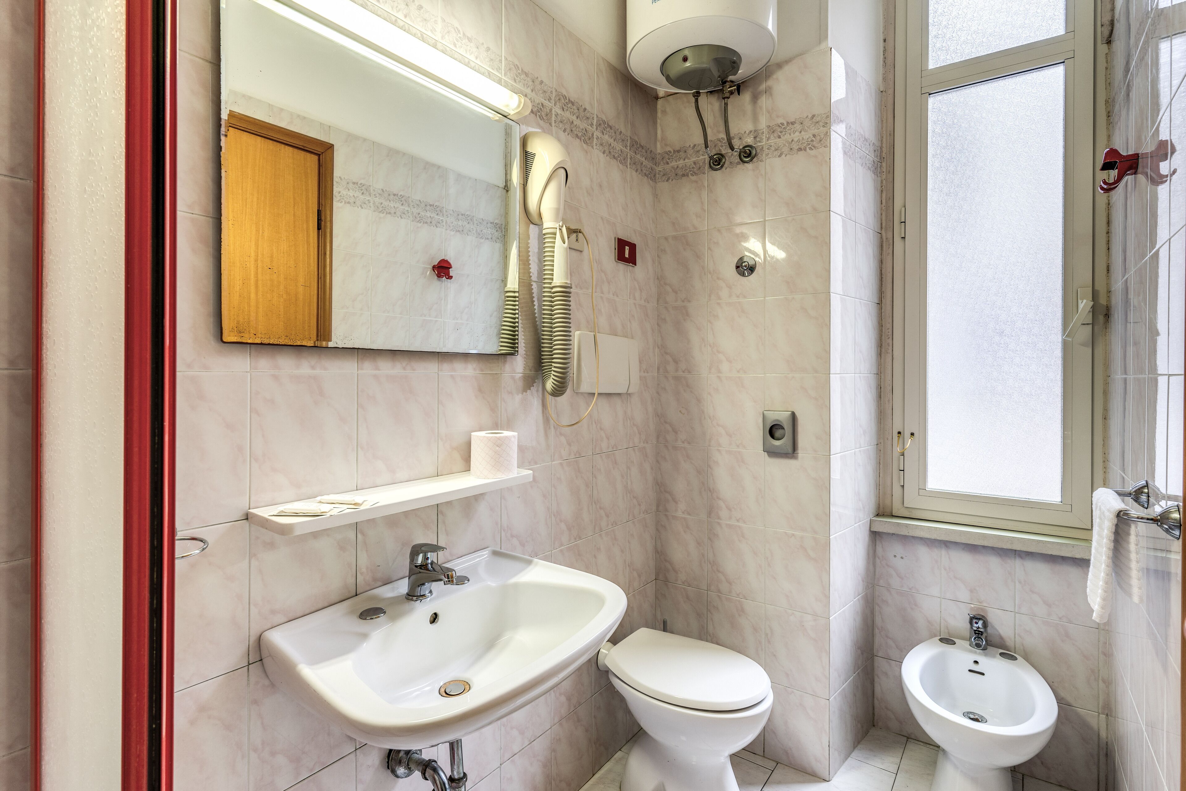 Un baño con lavamanos, inodoro, bidé y espejo.