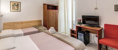 A hotel room with two beds, a wooden wardrobe, a desk with a television, and a red chair.