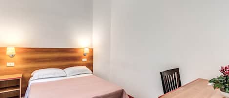 A hotel room with a bed, bedside tables, a desk, and a chair.